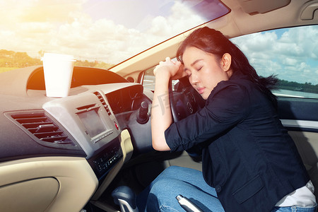 疲惫开车摄影照片_疲惫的年轻女子在车里睡着了