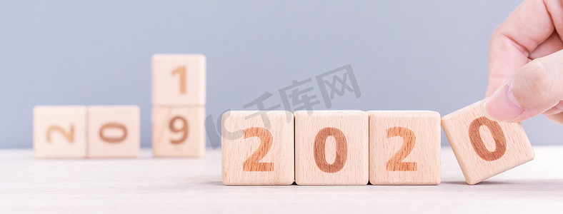 摘要2020年和2019年新年倒计时设计概念-妇女在木桌和蓝色背景上拿着木块立方体，特写，复制空间。