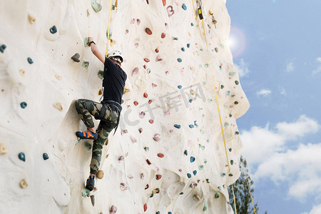 户外攀岩运动活动概念：人工攀岩墙上的男子攀岩者