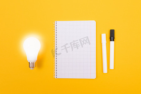 黄色桌子上放着记事本的发光节能灯