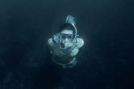 深海蜜柚摄影照片_在深海水下游泳的人。