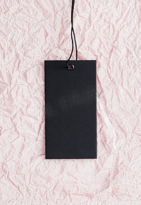 粉红纸背景上的黑色服装标签、可持续时尚和品牌标签概念