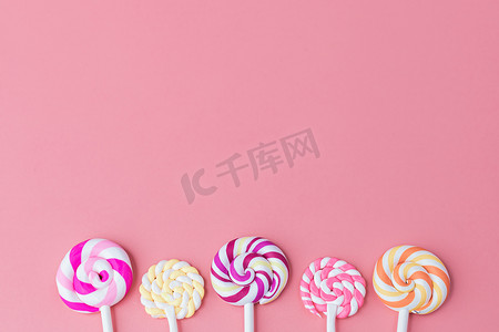 棒棒糖粉色背景摄影照片_粉红色背景中美味多彩的棒棒糖