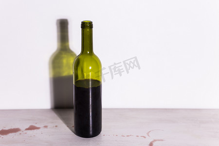鹿酒摄影照片_一瓶酒，桌上有一滩红色的酒。