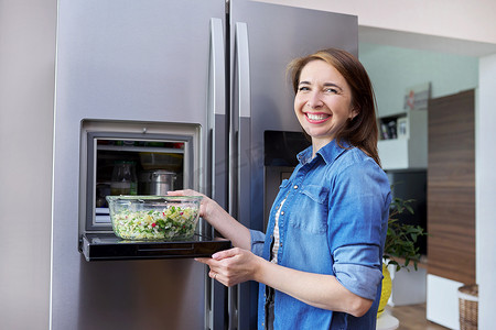 从冰箱里拿出一碗蔬菜沙拉的女人。