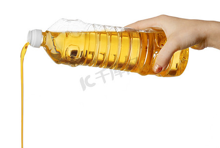 倒油瓶摄影照片_从塑料瓶中倒食用油的女人的手。