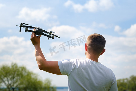 一个手里拿着飞行器的人，在大自然中升向天空。发射无人机