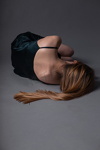穿裙子的女孩躺在地板上，头转过身去。