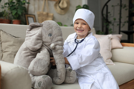 可爱的孩子打扮成医生玩玩具大象，用听诊器检查它的呼吸。