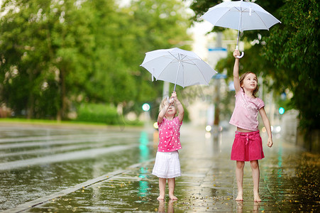 两个可爱的小姐妹在雨下玩得很开心