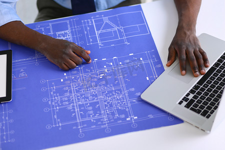 非洲裔美国建筑师在办公室使用计算机和蓝图