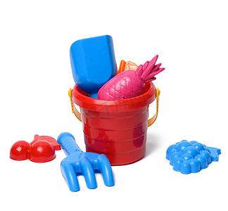 婴儿红色塑料桶用铲子和玩具隔离在白色背景。