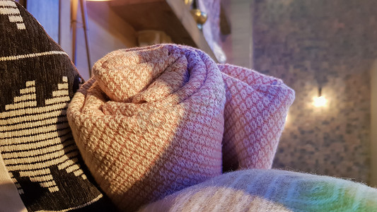 针织的温暖毯子被折叠起来并放在靠近壁炉的柳条篮中。