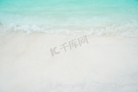 背景阳光沙滩摄影照片_夏季，沙子和水干净的海滩和白色沙滩的顶视图，阳光浅蓝色的天空和散景背景。