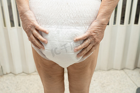 亚洲老年或老年老太太妇女病人在护理医院病房穿着失禁尿布，健康强大的医疗理念。