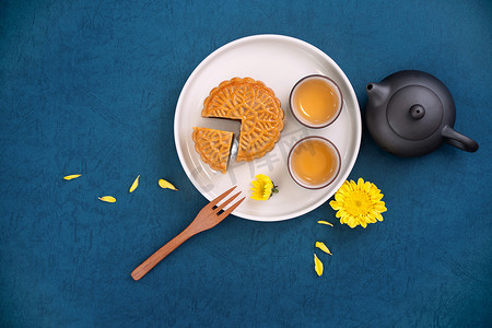 简约月亮摄影照片_中秋节蓝色背景的简约布局月饼，创意食品设计理念，顶视图，平躺，复制空间。