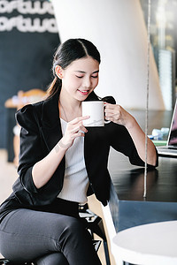 一位女营销经理正在喝杯咖啡休息，然后返回工作岗位以减少睡意。
