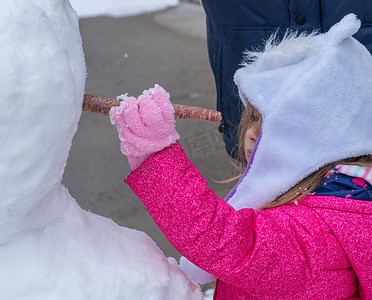 将胡萝卜放入雪人脸上的幼儿女孩