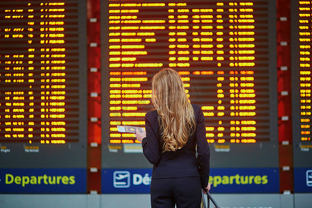 国际机场航站楼提着手提行李的妇女正在查看信息板