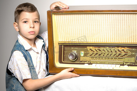 旧收音机摄影照片_旧收音机旁边的一个小男孩。