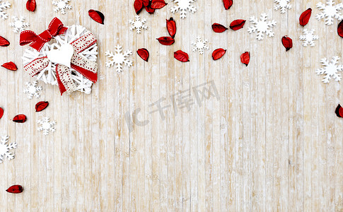 平躺着破旧的圣诞复制空间，在浅色木质背景下，左上角有白色木质雪花、红色花瓣和白色木质装饰心