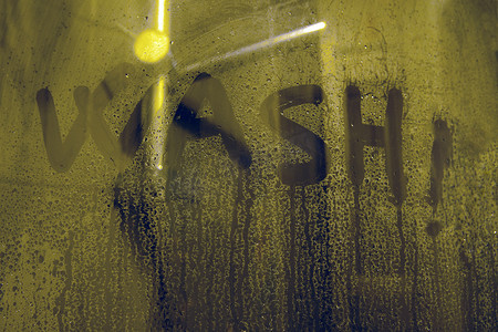 淋浴玻璃上的“洗”字母 — 手写字母写在带有水滴的灰色表面上。肥皂玻璃上的铭文 — 洗。
