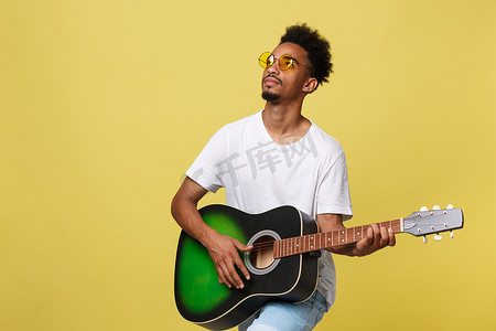 音乐家合影摄影照片_快乐的非洲裔美国音乐家在金黄色背景下用吉他合影。
