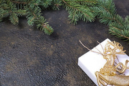 开业大吉金字摄影照片_冷杉树枝、金丝带、黑色牛皮纸礼品盒的圣诞组合，带有金色浮雕背景和文字位置。