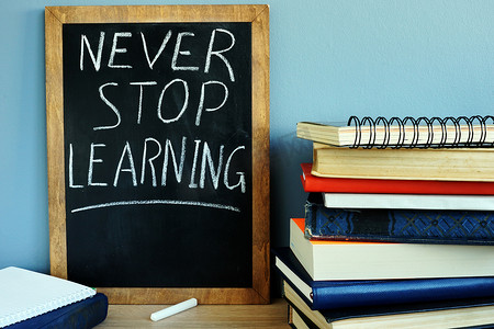 黑板上有标志永远不要停止学习和书籍。