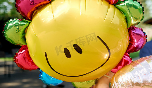 可爱的太阳表情摄影照片_带着微笑的黄色气球看起来像晴天