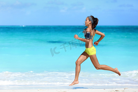 军对臂章摄影照片_带手机运动臂章的健身跑步女子沙滩跑步听音乐