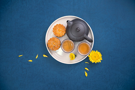 创意背景简约摄影照片_中秋节蓝色背景月饼的简约布局，创意食品设计理念，顶视图，平躺，复制空间。