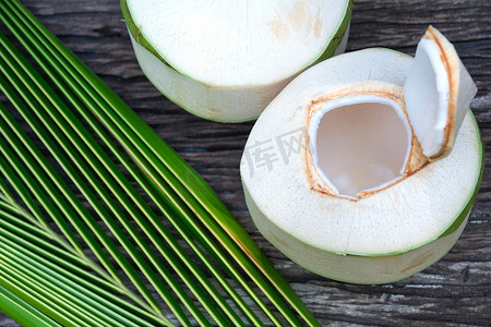 新鲜椰子水摄影照片_新鲜的有机椰子水与椰子叶在木桌上。