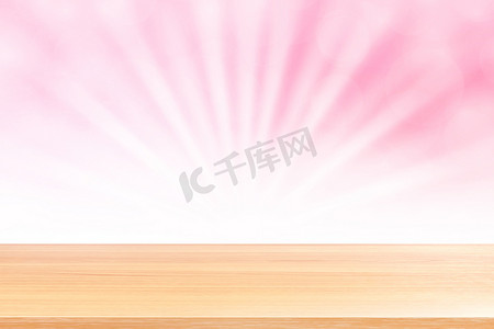 粉红渐变摄影照片_空木桌地板上柔和的粉红色散景灯光束闪耀渐变背景，木板空在粉红色散景彩色灯光照耀下，粉红色彩色散景灯渐变柔和，用于横幅广告