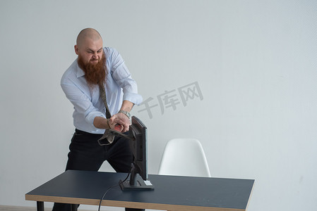 行政文员摄影照片_强调疯狂的商人在办公室使用斧头问题概念砸碎他的电脑。