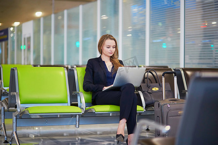 在国际机场使用笔记本电脑工作的女商人