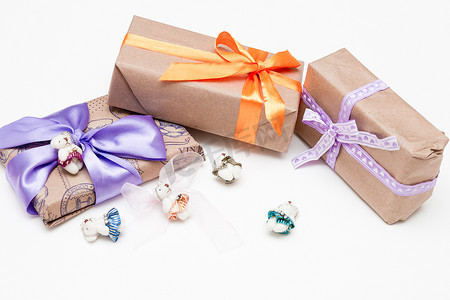 白色背景盒子里的礼物复制顶视图金色丝带，蝴蝶结包裹在棕色纸紫色丝带编织可爱熊装饰