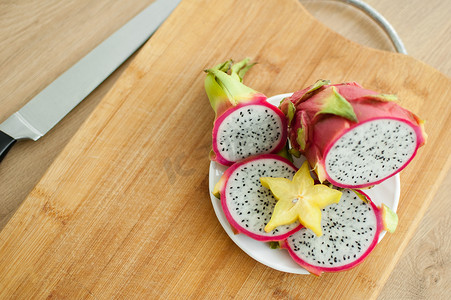 白色果肉和黑色种子的火龙果或火龙果片，在白盘上放一片杨桃或杨桃。