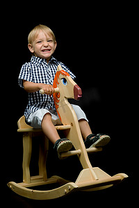 骑木马的男孩摄影照片_一个小男孩骑着一匹木马