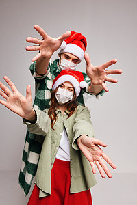 快乐的年轻夫妇戴着医用面具过圣诞节，手牵手过新年