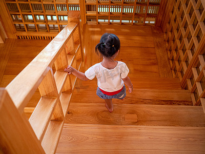 亚洲小女孩在 Hinoki Land 的木楼梯上行走；