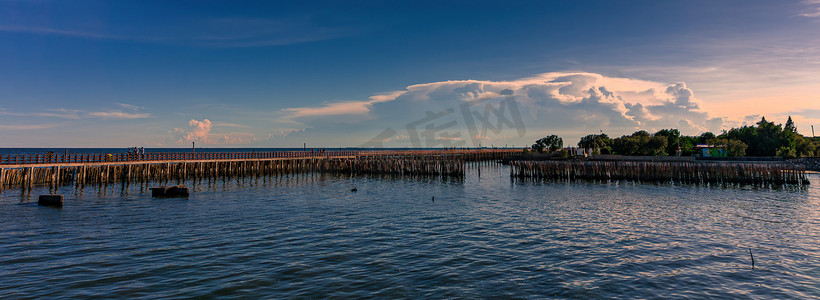 红色云摄影照片_沿着海边的长长的红色木桥和竹子是抵御海浪的海岸线保护。
