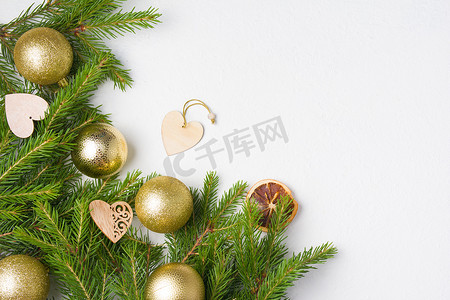 树枝状水系摄影照片_圣诞树金球和白色背景顶视图复制位置上的天然杉树枝，新鲜云杉树枝上的木制生态友好型圣诞树玩具