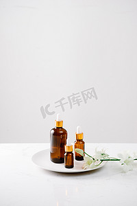 滴瓶样机摄影照片_白色表面上的有机兰花纯油滴瓶，背景是兰花头。