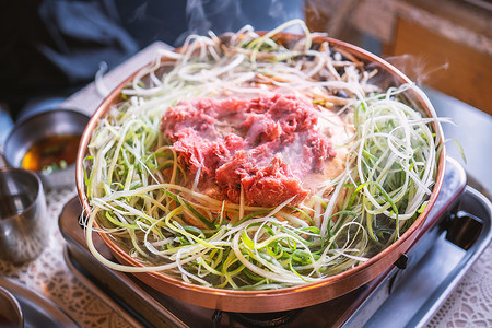首尔韩国餐厅的牛肉烧烤烤肉，铜锅上的生活方式新鲜韩国美食，带切片烤架，特写，复制空间