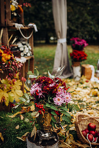 鲜花拱门摄影照片_秋季婚礼在绿色草坪上的街道上举行。仪式上装饰着鲜花拱门