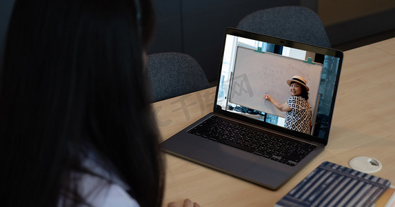 远程会议虚拟摄影照片_由于新冠疫情，亚洲年轻女学生通过远程会议向学校老师学习虚拟互联网在线课程。