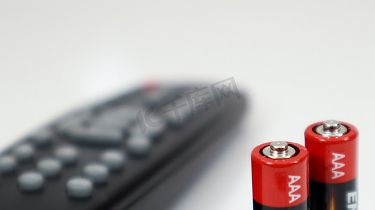 有在红色和白色的AAA碱性电池的黑电视遥控在白色背景。