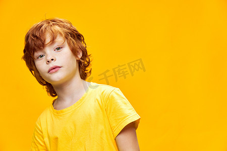 一个红发男孩在孤立的背景下弯腰的肖像