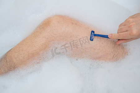 一张有趣的照片，一个男人正在放松地洗澡并刮腿毛。